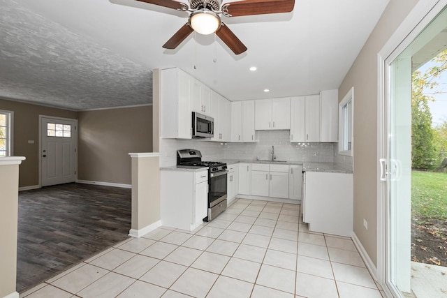 kitchen featuring decorative backsplash, light wood-type flooring, stainless steel appliances, sink, and white cabinets