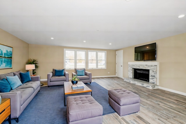 living room with light hardwood / wood-style floors and a stone fireplace