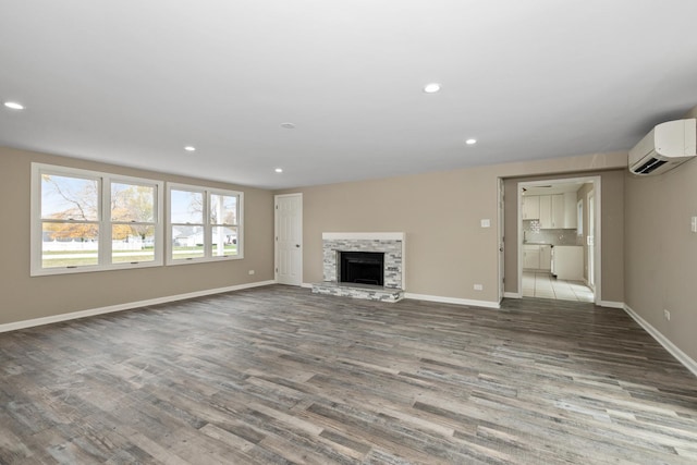 unfurnished living room with a wall unit AC, a fireplace, and wood-type flooring