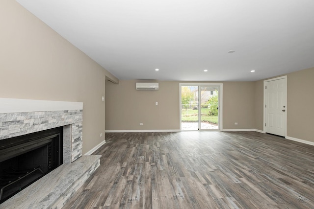 unfurnished living room with a wall mounted air conditioner, dark hardwood / wood-style floors, and a stone fireplace