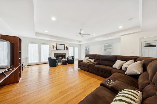 living room featuring a tray ceiling, light hardwood / wood-style floors, and ceiling fan