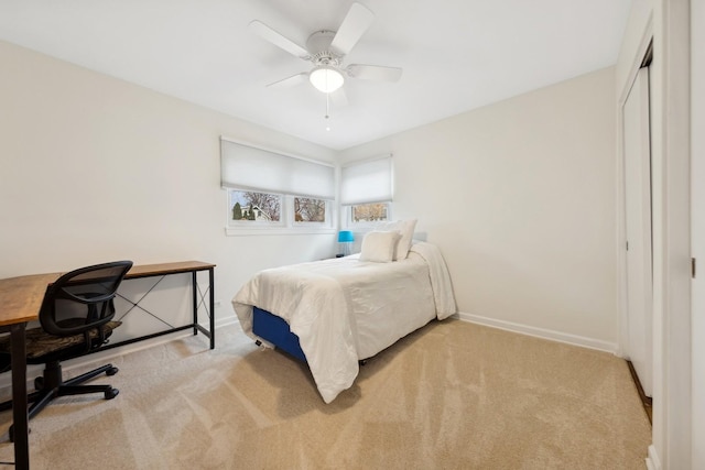 bedroom featuring light colored carpet, ceiling fan, and a closet