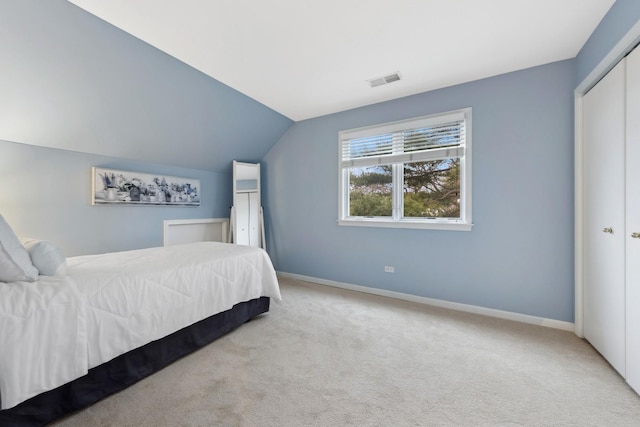 carpeted bedroom with lofted ceiling and a closet