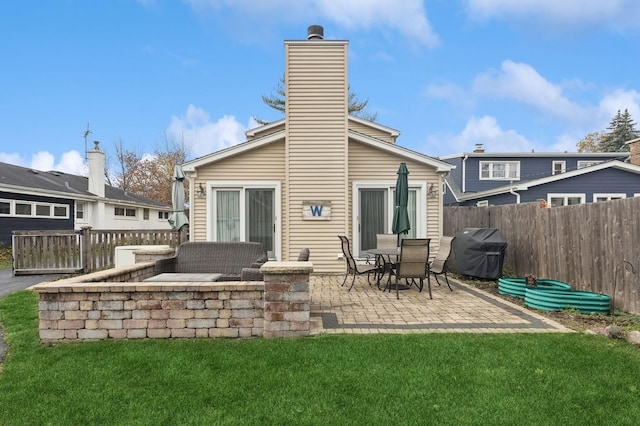 rear view of house with a patio and a lawn