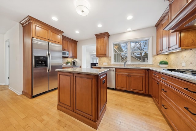 kitchen with sink, appliances with stainless steel finishes, a center island, light stone countertops, and custom exhaust hood