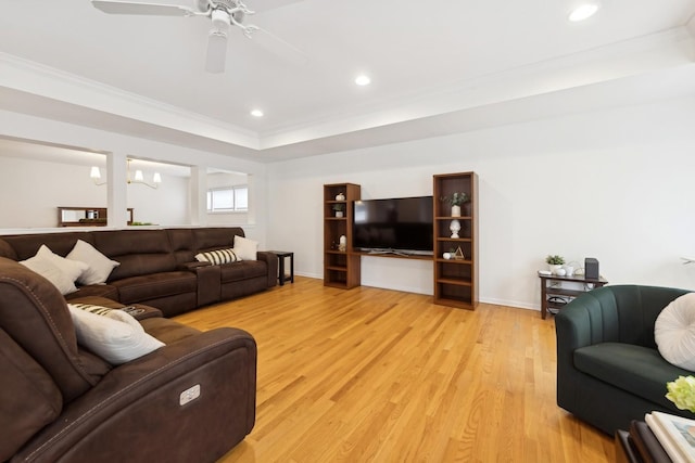 living room with ceiling fan with notable chandelier, ornamental molding, and light hardwood / wood-style floors