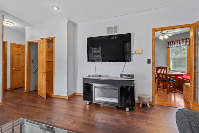 living room with ceiling fan and dark wood-type flooring