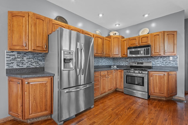 kitchen featuring decorative backsplash, appliances with stainless steel finishes, and dark hardwood / wood-style flooring