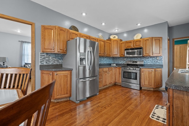 kitchen with hardwood / wood-style flooring, decorative backsplash, and appliances with stainless steel finishes