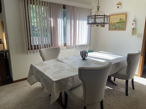 dining area with carpet and a notable chandelier