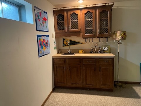 bar featuring sink, dark brown cabinetry, and light carpet