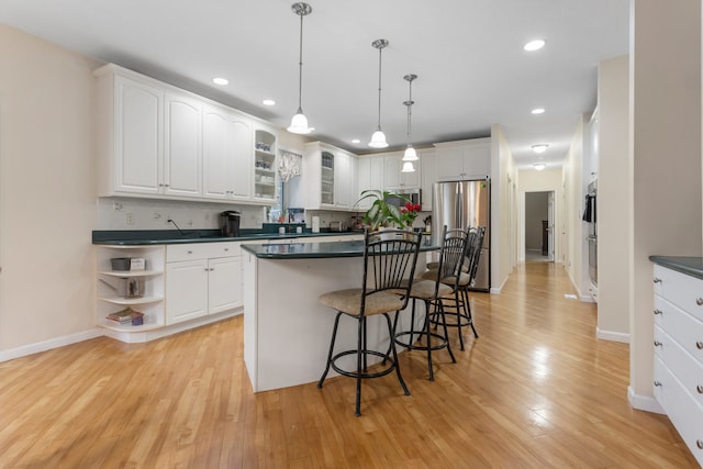 kitchen with white cabinets, decorative light fixtures, light hardwood / wood-style floors, and appliances with stainless steel finishes