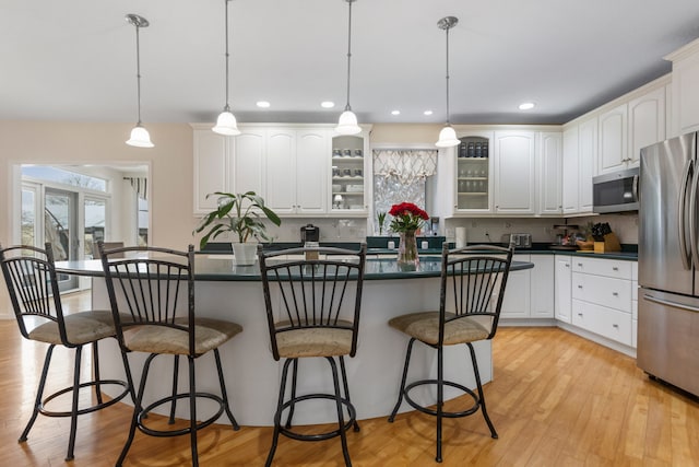 kitchen with white cabinets, decorative backsplash, stainless steel appliances, and hanging light fixtures