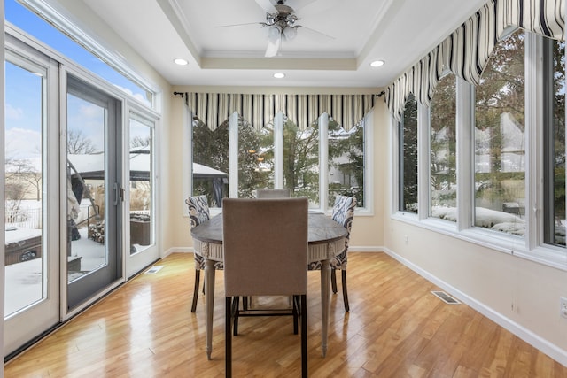 sunroom featuring ceiling fan, a raised ceiling, and plenty of natural light