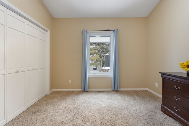 unfurnished bedroom with a closet and light colored carpet