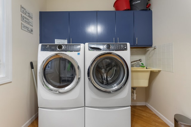 clothes washing area featuring hardwood / wood-style floors, cabinets, sink, and washing machine and clothes dryer