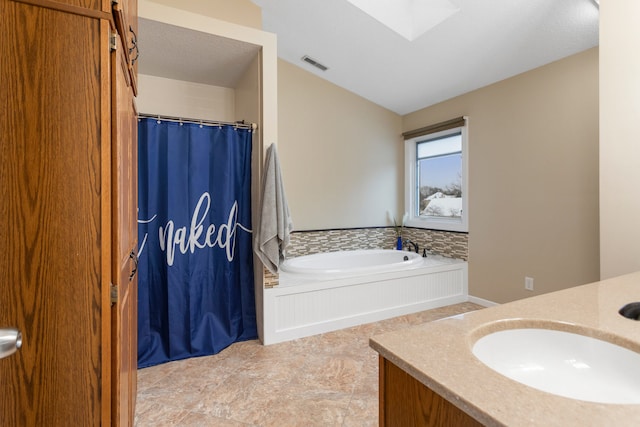 bathroom featuring a tub to relax in, a skylight, and vanity