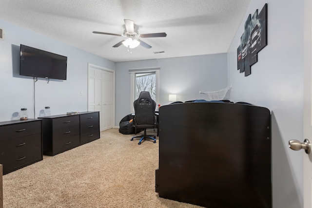 carpeted home office with ceiling fan and a textured ceiling