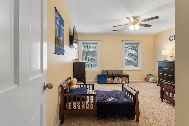 carpeted bedroom featuring ceiling fan, a textured ceiling, and multiple windows