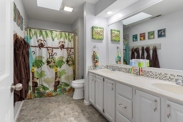 bathroom featuring vanity, toilet, a skylight, and tasteful backsplash