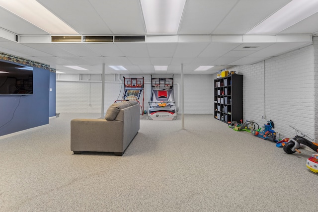 basement featuring a drop ceiling and brick wall