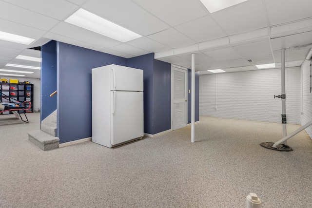 basement featuring a paneled ceiling, white fridge, and carpet