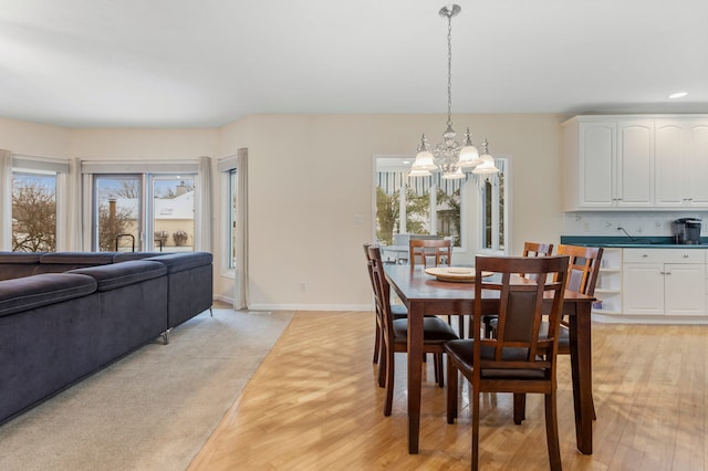 dining space featuring light carpet and an inviting chandelier