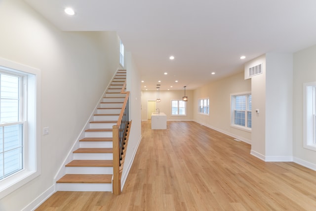 stairs featuring hardwood / wood-style floors and plenty of natural light