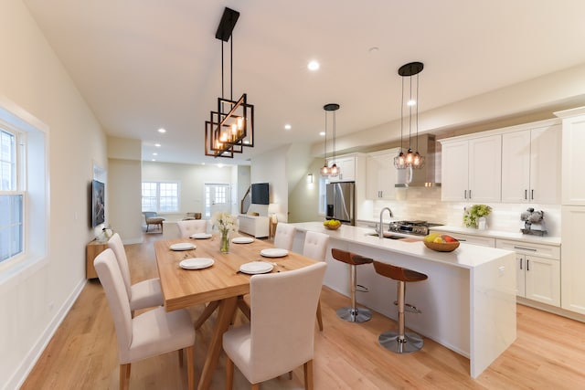 dining area featuring a wealth of natural light, sink, a chandelier, and light wood-type flooring