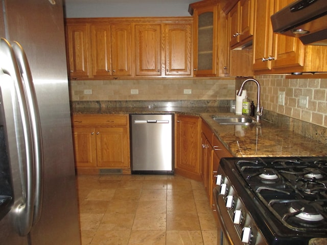 kitchen featuring stainless steel appliances, tasteful backsplash, dark stone counters, and sink