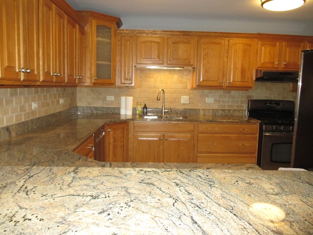 kitchen featuring ventilation hood, black gas stove, sink, stainless steel fridge, and light stone countertops