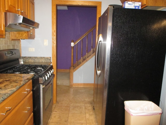 kitchen with light stone countertops, appliances with stainless steel finishes, and backsplash