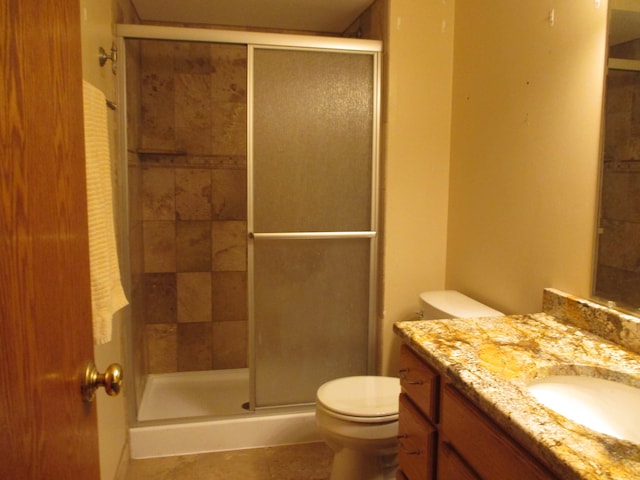 bathroom featuring tile patterned flooring, vanity, toilet, and a shower with door