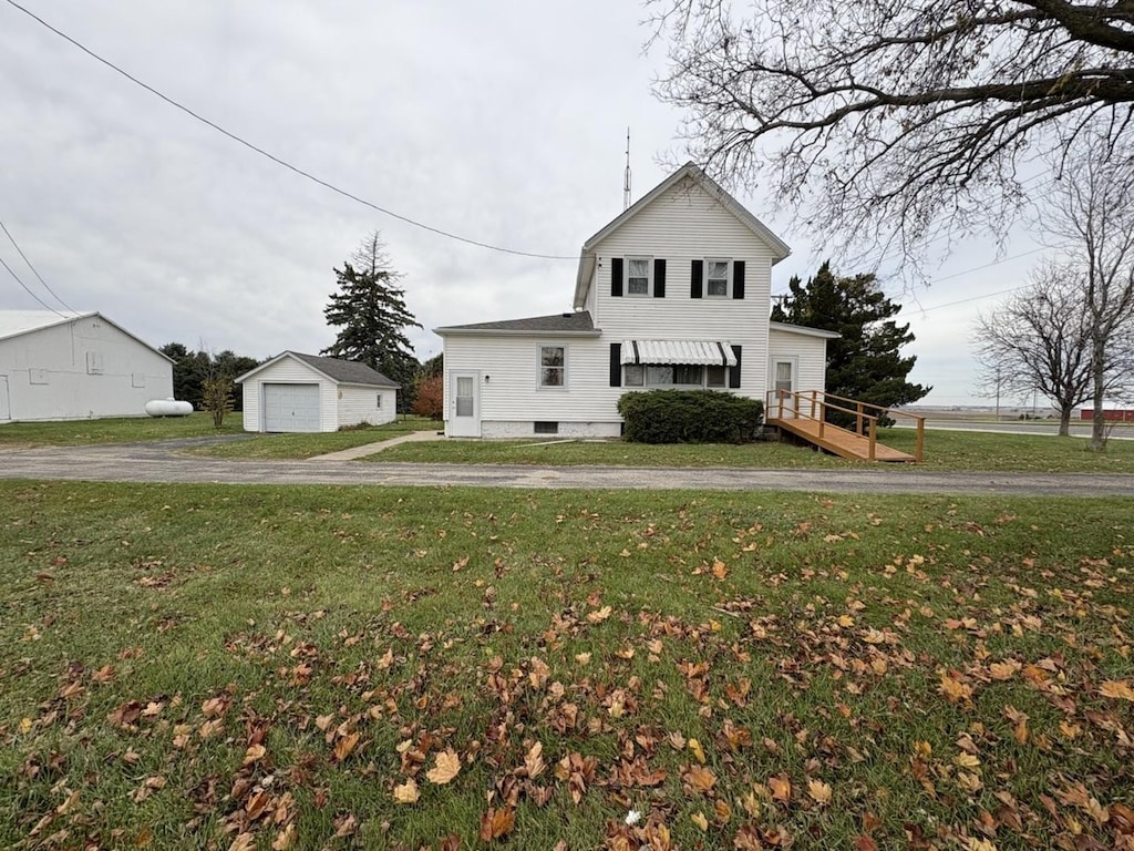 view of property featuring a garage, an outbuilding, and a front yard