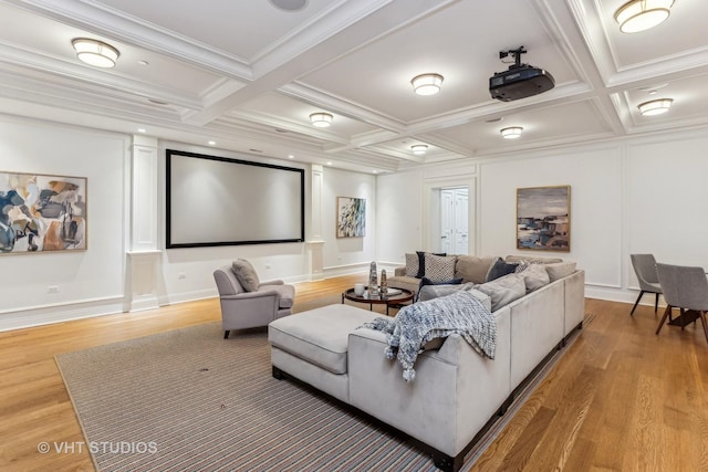 cinema room with light wood-style floors, coffered ceiling, beamed ceiling, and crown molding