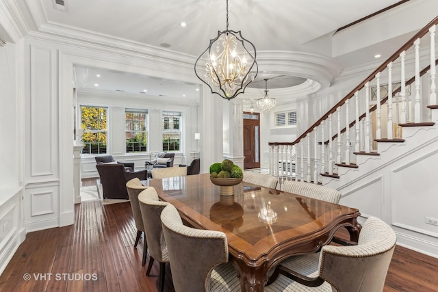 dining area featuring crown molding, a notable chandelier, a decorative wall, and stairs