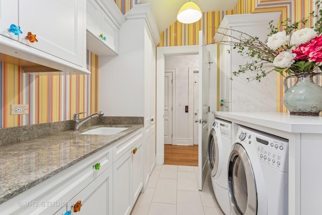 laundry room featuring cabinet space, light tile patterned flooring, a sink, separate washer and dryer, and wallpapered walls