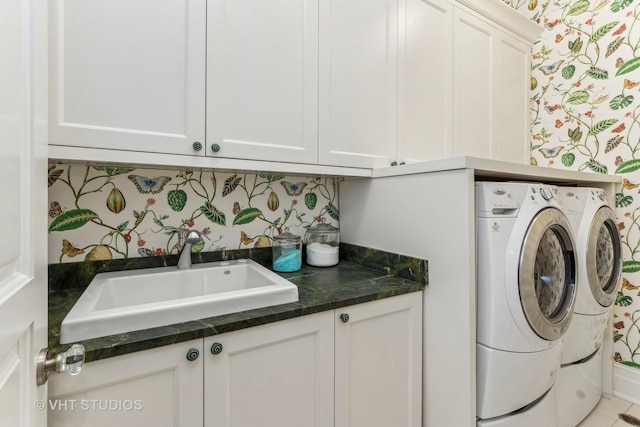 laundry room featuring a sink, wallpapered walls, cabinet space, and washer and dryer