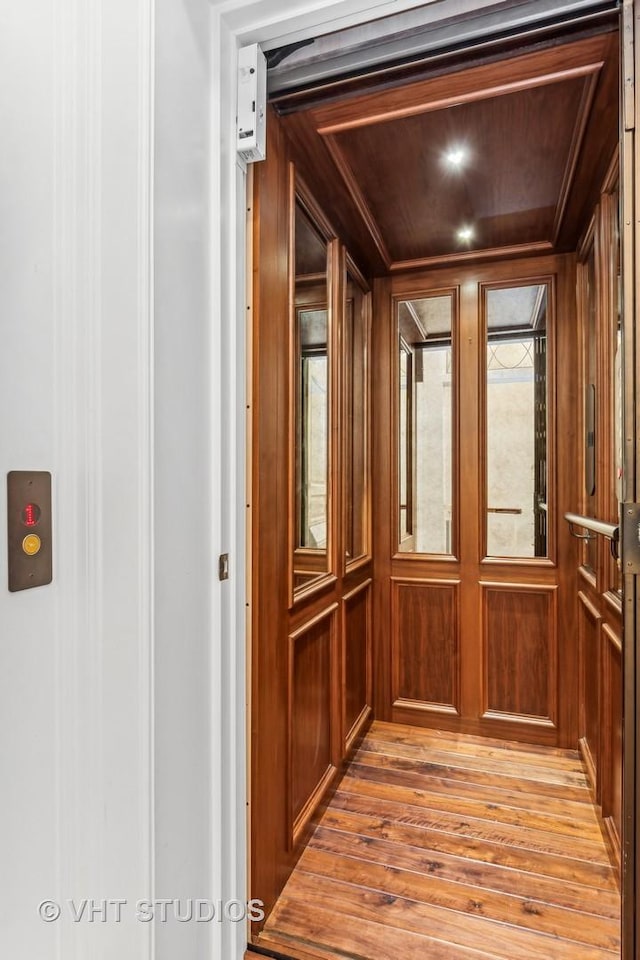 room details with elevator, wood walls, and wood finished floors