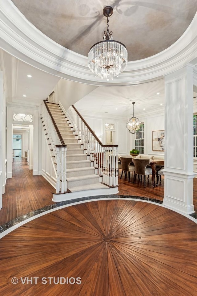 foyer entrance with a chandelier, hardwood / wood-style flooring, recessed lighting, stairs, and crown molding