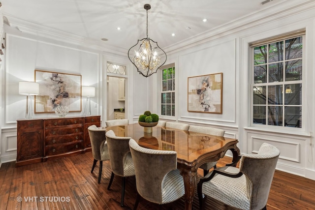 dining room with ornamental molding, a healthy amount of sunlight, a decorative wall, and dark wood-style floors