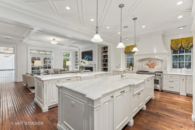 kitchen with high end range, open floor plan, a kitchen island with sink, custom exhaust hood, and a fireplace