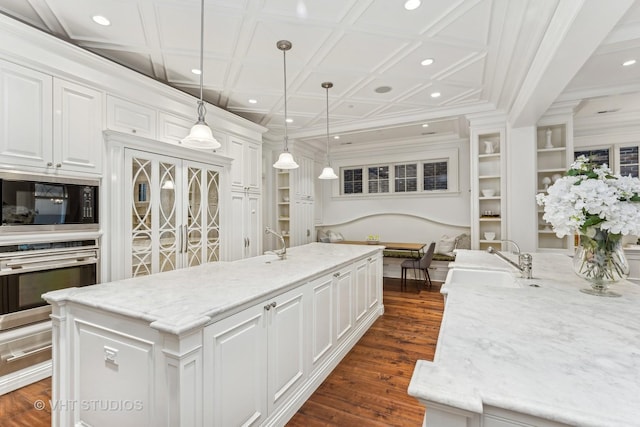 kitchen featuring built in microwave, white cabinetry, stainless steel oven, and a sink