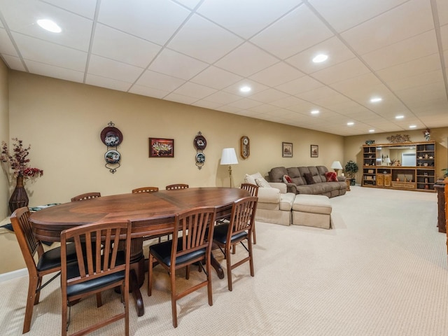 carpeted dining space with a paneled ceiling