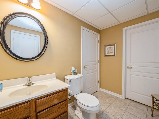 bathroom featuring tile patterned flooring, a paneled ceiling, vanity, and toilet