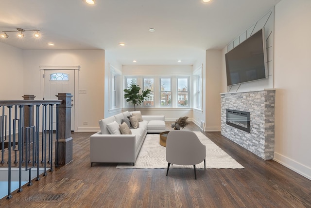 living room featuring a stone fireplace and dark wood-type flooring