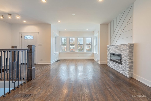 living room with a stone fireplace and dark hardwood / wood-style flooring