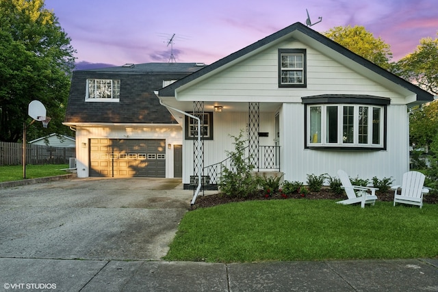 view of front of home with a porch, a garage, and a yard