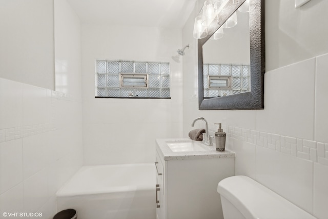 full bathroom featuring vanity, toilet, tile walls, and tiled shower / bath combo