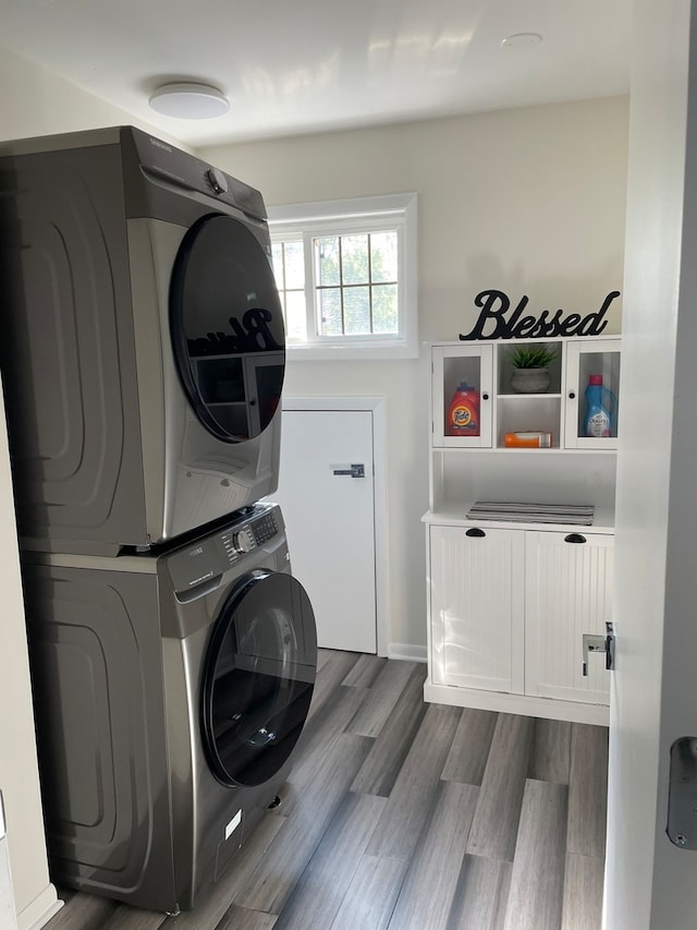 washroom with wood-type flooring and stacked washer / drying machine